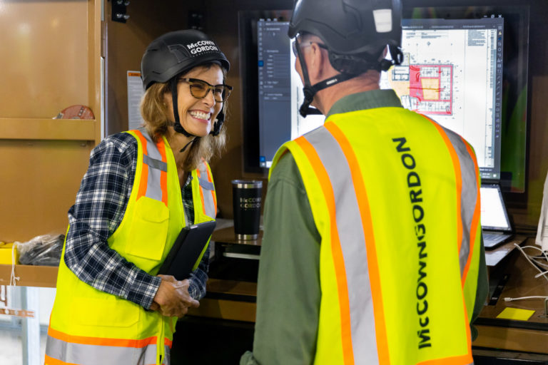 Two McCownGordon Construction associates laughing and collaborating while looking at plans on a job site