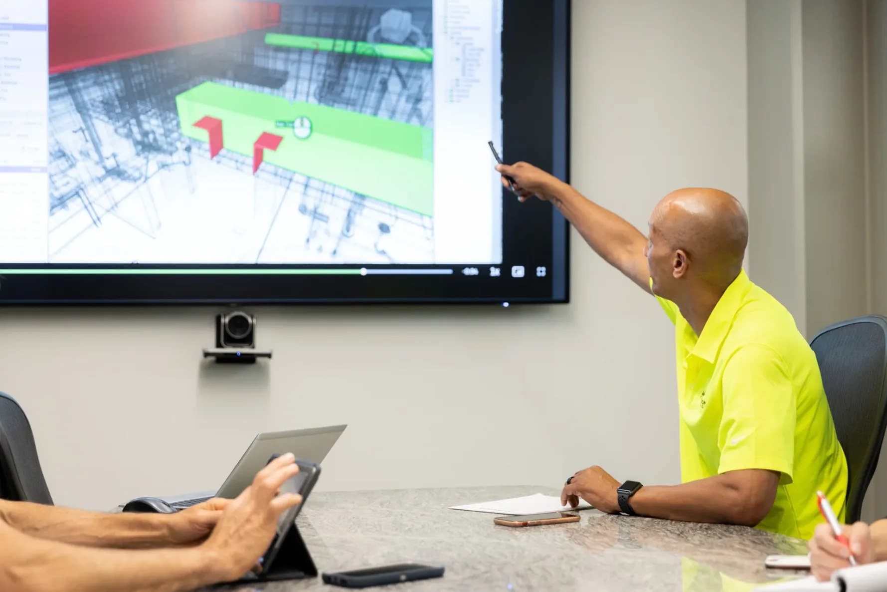 A McCownGordon Construction associate pointing to plans on a screen while in a meeting
