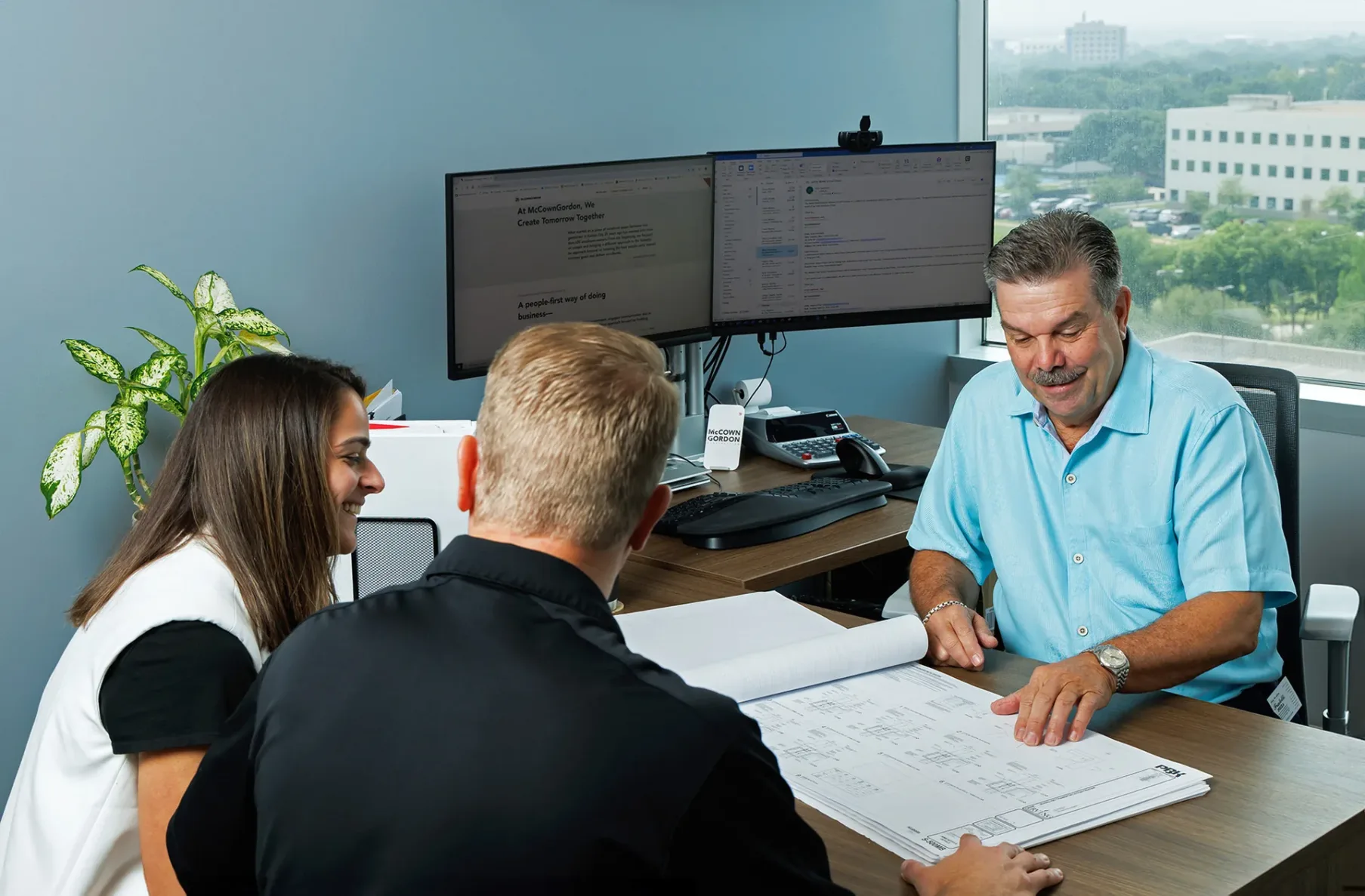 Three McCownGordon associates looking at construction drawings and having a meeting in an office