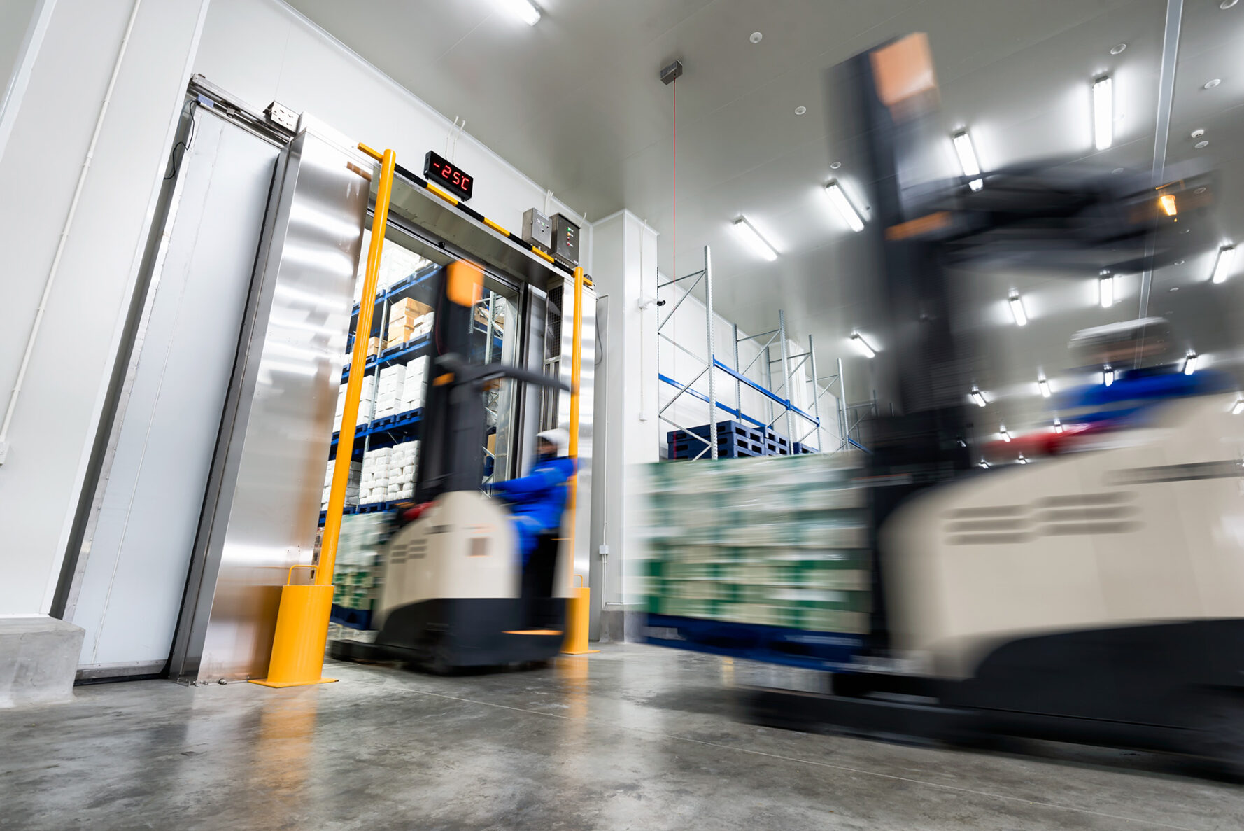 Worker Stand-on stacker truck used to lift and move the ready meals goods stock in cold storage