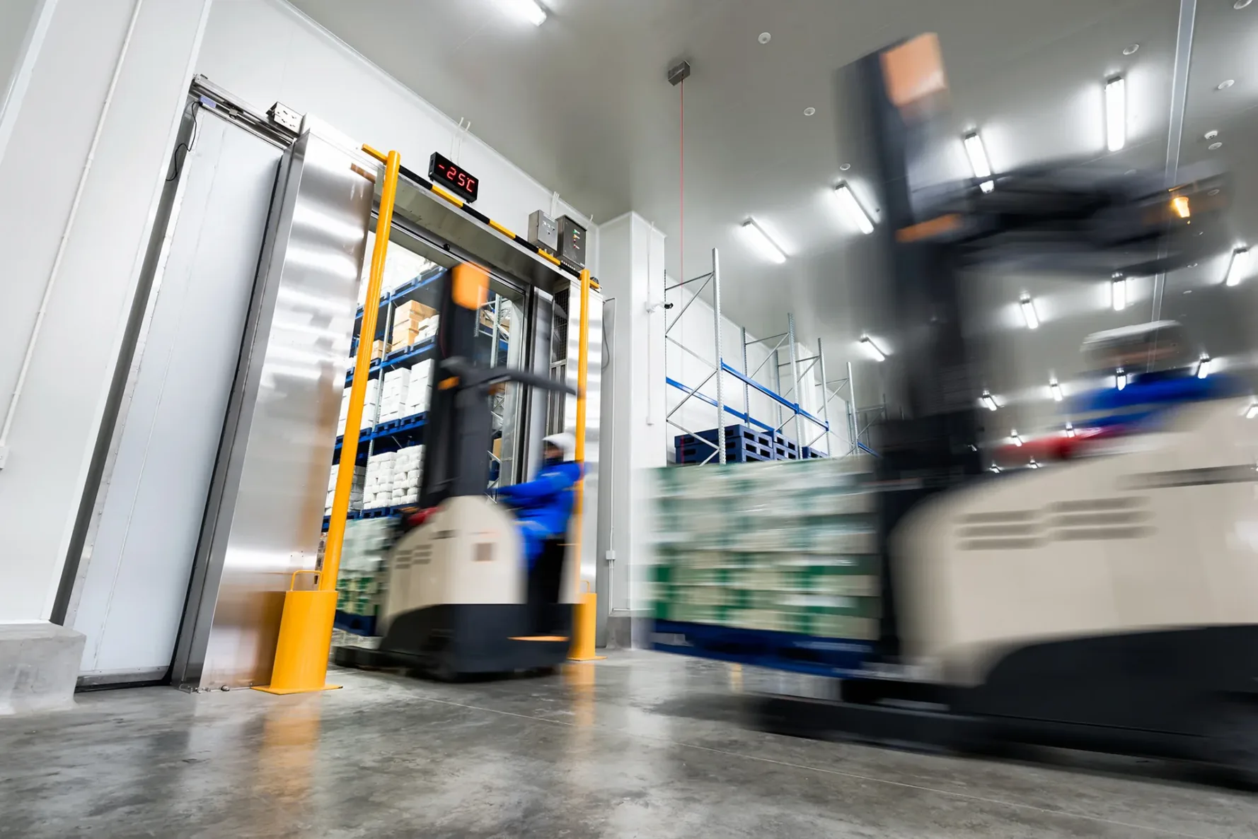 Worker Stand-on stacker truck used to lift and move the ready meals goods stock in cold storage